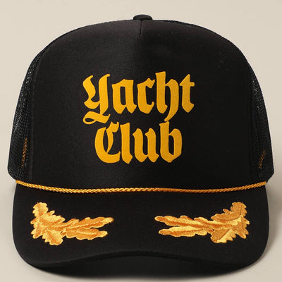 The Fashion City Yacht Club Trucker Hat features bold yellow Gothic lettering on a black front, gold leaf embroidery, a braided rope above the brim, and a breathable mesh back for classic style and comfort.