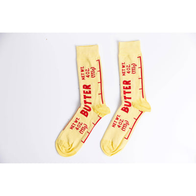 Yellow Owl Workshop’s Butter Crew Socks - Large are buttery-soft yellow socks styled like butter sticks, with red “BUTTER” and “NET WT. 4 OZ (113g)” text on the sides—ideal for a fun, kitchen-themed gift.