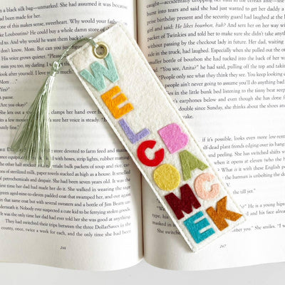 The Welcome Back Felt Bookmark by Milo & Mollie features bold rainbow WELCOME letters and a light green tassel—handmade and vibrant, its the perfect gift for book lovers.