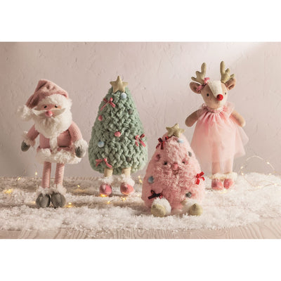 Mud Pie’s Holiday Plush Pals—a pink Santa, green and pink Christmas trees, and a reindeer in a pink dress—stand on faux snow amid string lights, crafted from soft minky plush against a light background.