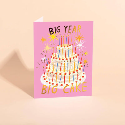The Carolyn Suzuki Gigantic Cake Birthday Card features a large, festively decorated tiered cake with candles, BIG YEAR at the top, and BIG CAKE in gold foil at the bottom amid starbursts.
