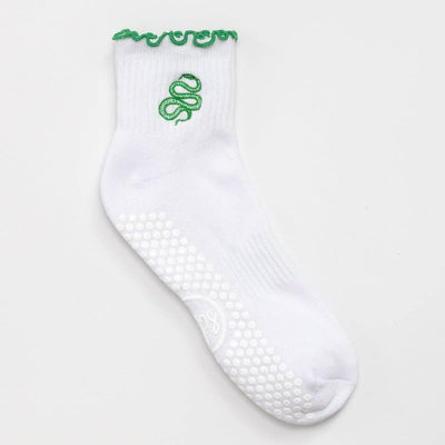 The Reformer Loops Snake Ruffle Pilates Grip Socks are white with green ruffled trim and an embroidered snake design. White grip dots on the sole offer extra stability during workouts.