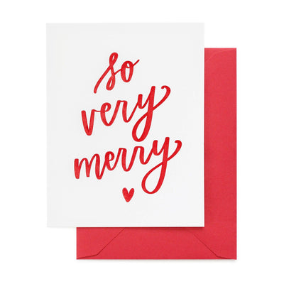 The So Very Merry Greeting Card by Sugar Paper features red cursive text and a small heart, letterpress printed on white card stock, and comes with a matching red envelope.