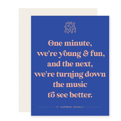 Paloma Paper Co.s Turn Down To See Better Birthday Card features a blue design with peach text: One minute, were young & fun, and the next, were turning down the music to see better. Music notes/stars float above. Below: It happens quickly.
