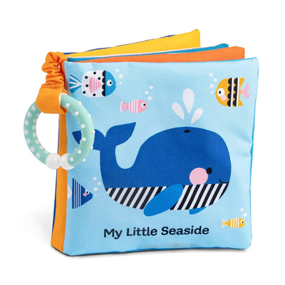 My Little Seaside Childrens Cloth Book by Wendy Kendall (Hachette Book Group) is a soft fabric sensory book with a blue whale and colorful fish on the cover, plus a light blue teething ring on its crinkly corner.