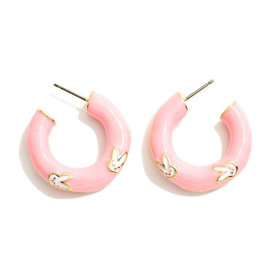 Judson & Companys Easter Enamel Hoop Earrings are pink enamel-coated hoops featuring white bunny designs with golden outlines, offering a shiny finish and metal posts for easy wear.