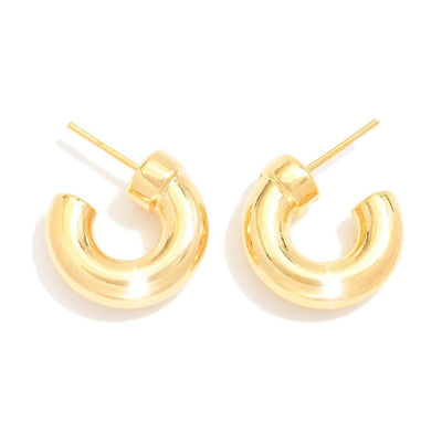 The Riya Chunky Gold Hoop Earrings by Judson & Company are shiny, 18k gold-filled with a thick, curved design on a white background. Made in Brazil, they feature hypoallergenic post backings for sensitive ears.