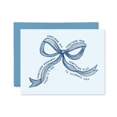 The Something Borrowed Something Blue Card by Pretty by Her features a blue envelope and bow illustration on premium cardstock. The bow reads: Something old, something new, something borrowed, something blue—today is a day to celebrate you.