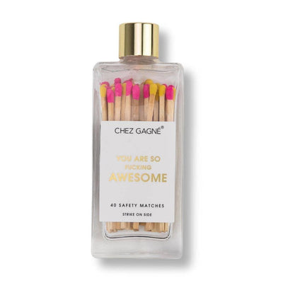 The Chez Gagné Youre So Fucking Awesome Glass Bottle Matches features a clear glass bottle with a gold cap, 40 pink and yellow-tipped safety matches, side strike, and label that reads: You are so fucking awesome.