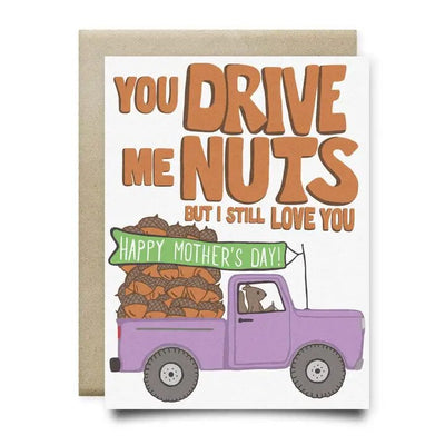 Anvil Cards Drive Me Nuts Mothers Day Card is an A2 card with a hand-drawn cartoon of a purple truck filled with nuts and a dog driver. The message reads, You drive me nuts but I still love you. Happy Mothers Day! Crafted on sustainable linen paper, it includes a brown envelope.