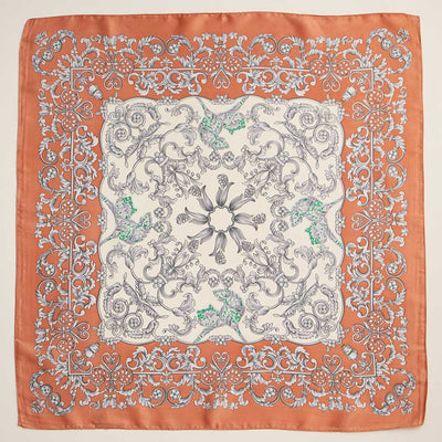 The Sensibling Corp. Baroque Scroll Printed Square Silky Satin Scarf in Rust features gray, white, and green floral and scroll motifs on a cream background with a burnt orange border and detailed white accents.