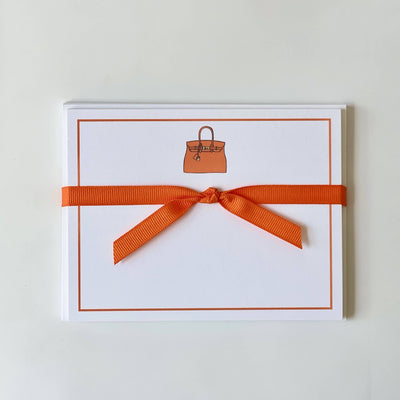 Georgetown Paperies Orange Bag - Flat Note Cards are made from ultra white paper stock, tied with an orange ribbon, and feature a chic handbag illustration at the top center for a pristine presentation.