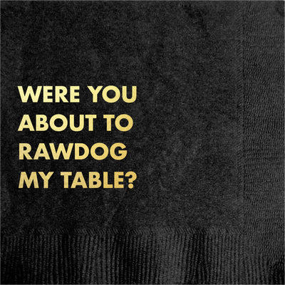 The Pretty Alright Goods Rawdog Table Cocktail Napkin features gold text—"WERE YOU ABOUT TO RAWDOG MY TABLE?"—on a luxe, dark textured background, resembling elegant black and gold cloth for a premium party look.