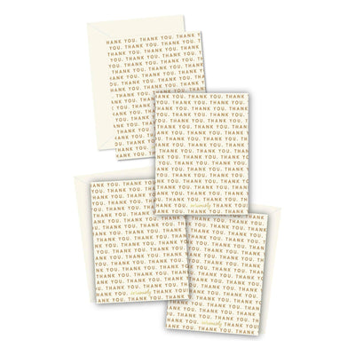The Repeating Thank You Cards - Boxed Set by Ginger P. Designs includes four gold foil cards with matching envelopes, featuring a gold on white THANK YOU pattern. The blank cards are arranged overlapping in the box.