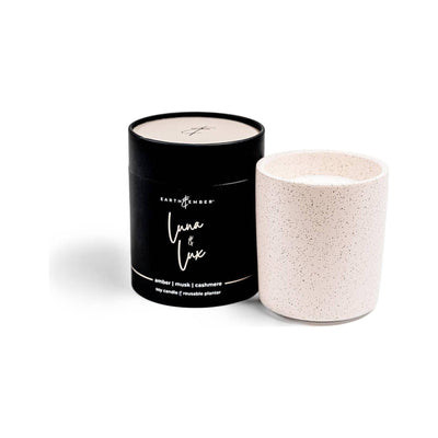 The Earth & Ember 13 oz Candle: Luna & Lux by Milkhouse Candle Company features a white speckled soy wax in a ceramic holder, with notes of amber, musk, and cashmere—perfect as a gift and reusable as a planter.