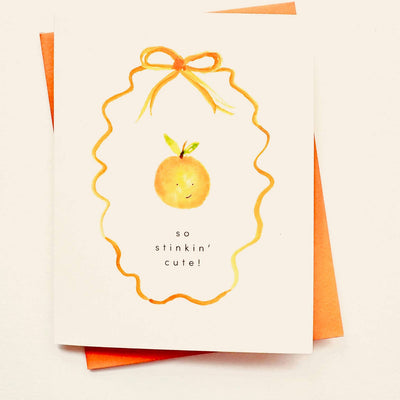 The Cutie Baby Stinkin' Cute Card Congratulations by Sweet Julie Marie features a hand-watercolored smiling orange, an orange ribbon, and "so stinkin cute!" text on cute stationery with an orange envelope.