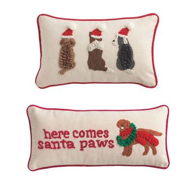 The Mud Pie Christmas Dog Hooked Wool Pillows set includes one pillow with three dogs in Santa hats, one with a dog in a wreath scarf and here comes santa paws text, both finished with festive red piping.