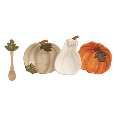 The Mud Pie Pumpkin Triple Tidbit Set features three ceramic pumpkin-shaped dishes in beige, white, and orange, plus a mango wood spoon with a green leaf handle detail—all displayed on a crisp white background.