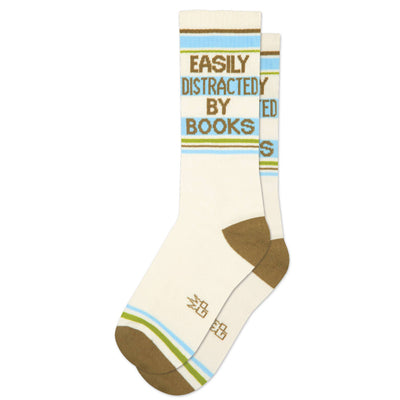 Gumball Poodle's Easily Distracted By Books Gym Crew Socks feature a cozy cream base with blue, green, and brown accents, plus the phrase "EASILY DISTRACTED BY BOOKS," making them perfect for book lovers and lounging in style.