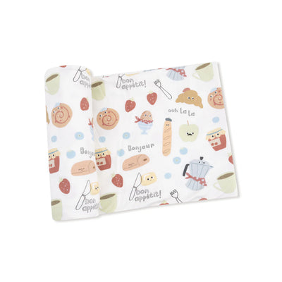 The Bonjour Breakfast Bamboo Stretch Knit Swaddle Blanket by Angel Dear features croissants, strawberries, coffee cups, and “Bonjour” hand-drawn on crisp white bamboo fabric—perfect as a soft swaddle or cozy baby blanket.