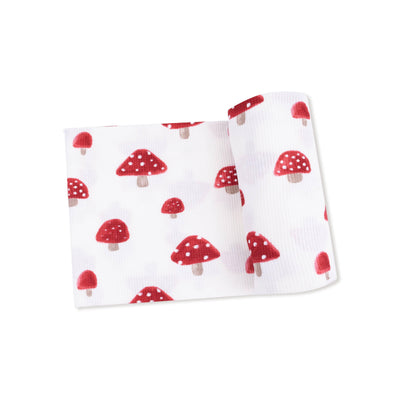 The Angel Dear Painterly Mushrooms Waffle Knit Swaddle Blanket is folded and features red and white spotted mushroom prints in various sizes, shown on a plain white background.