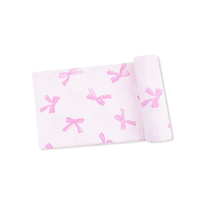 The Pretty Bows Ribbed Swaddle Blanket by Angel Dear is a soft, stretchy, light pink modal fabric featuring darker pink bows all over, shown folded on a white background.