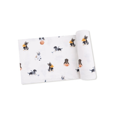 The Sporty Puppies Bamboo Stretch Knit Swaddle Blanket by Angel Dear features playful dog sports illustrations on a soft white bamboo fabric.
