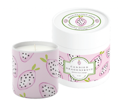 The Annapolis Candle Merriweather Grove Candied Dragonfruit Candle is a pink soy-based candle in a round box, both featuring original dragonfruit art. The label highlights passion fruit and mango notes.