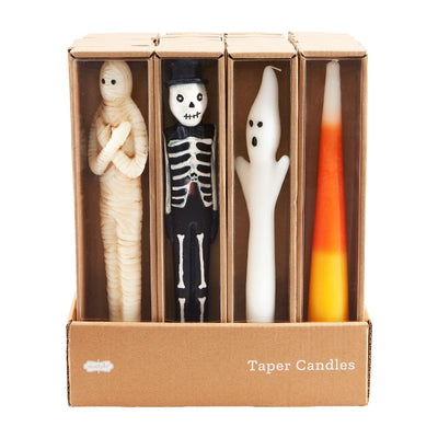 The Mud Pie Halloween Taper Candles set includes four 10 wax candles—mummy, skeleton in a top hat, ghost, and candy corn—in a “Taper Candles” box, perfect for adding festive charm to your decor.
