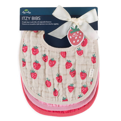 Three ultra-soft muslin cotton baby bibs with strawberry patterns are stacked and packaged. The top bib shows red strawberries on a beige background. A ribbon with a strawberry-shaped tag says Itzy Bibs. These are part of the Strawberries + Cream Itzy Bibs™ by Itzy Ritzy.