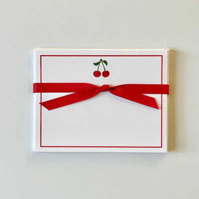 The Georgetown Paperie Cherry - Flat Note Cards are crafted on ultra white paper with a cherry illustration bordered in red. They come elegantly secured with a red ribbon bow and include matching envelopes, making them perfect for any occasion.