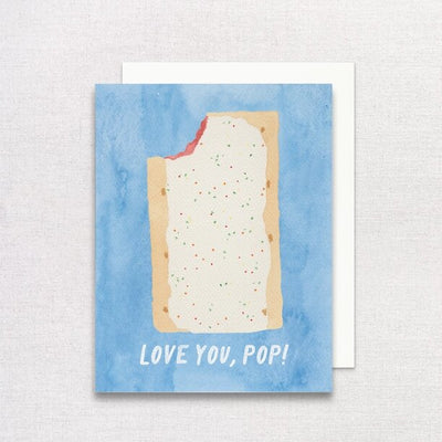 The Love You, Pop Greeting Card by Gert & Co features a partially eaten pastry illustration on a blue background with text reading LOVE YOU, POP! Its printed on recycled paper and comes with a partially visible white envelope behind the A2 card.