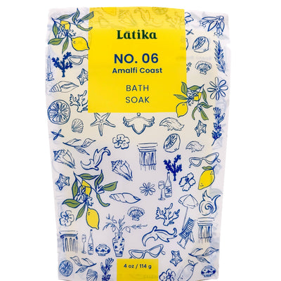 The Amalfi Coast Bath Soak by Latika Beauty offers a 4 oz (114 g) package with citrus and oceanic notes. It features blue and yellow illustrations of lemons, leaves, flowers, sea creatures, and shells, evoking an Italian vacation feel.