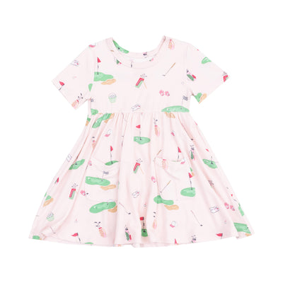 The Golf Things Pink Short Sleeve Twirly Dress by Angel Dear features a soft bamboo viscose fabric, a gathered skirt, and an all-over golf-themed print with clubs, balls, tees, and greens in green, red, and beige tones.