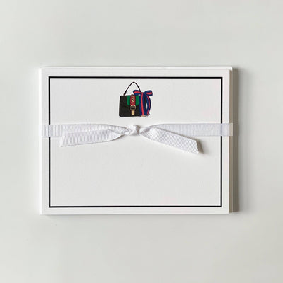 The Ribbon Bag - Flat Note Cards by Georgetown Paperie features a minimalistic design on ultra white paper with a handbag illustration and colorful scarf accent, tied with a white ribbon against a plain white background.