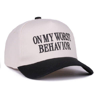 The 42POPS On My Worst Behavior Two Tone Baseball Cap features a white cotton design with a black brim, black embroidered "ON MY WORST BEHAVIOR" text, small BLACK print, and an adjustable strap. Stylish, lightweight, and comfortable.