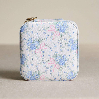 The Sensibling Corp. Flower Bow Pattern Travel Jewelry Box is a compact, vintage-inspired case with blue flowers and pink bows on a neutral background, plus a gold zipper for secure storage—perfect for travel.