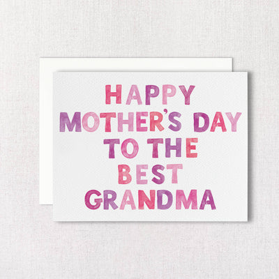 Gert & Cos Best Grandma Mothers Day Greeting Card features watercolor-style Happy Mothers Day to the Best Grandma text in pink and purple on textured white recycled paper. It includes a matching envelope partly visible behind the card.