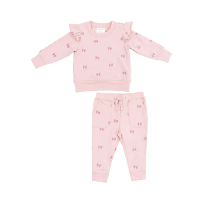 The Bows French Terry Ruffle Sweatshirt and Jogger by Angel Dear is a pink toddler set with bow patterns, a ruffle-shoulder long-sleeve top, and matching organic cotton joggers featuring a drawstring waist and side pockets.
