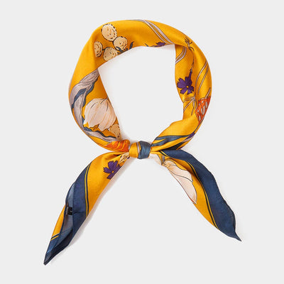 The Sensibling Corp. Flower Butterfly Printed Square Scarf, in yellow with white and purple floral prints plus navy accents, is tied loosely against a plain light background.