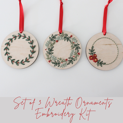 Three wooden wreath ornaments with embroidery and red ribbon from The HNB House are displayed in a row. Below, text reads: Set of 3 Christmas Wreath Ornament DIY Embroidery Kit—perfect for your own festive creations.