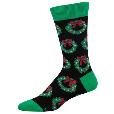 The Socksmith Christmas Wreath Men's Socks come in black, size 10-13, with green toe, heel, and cuff. Festive green wreaths with red bows and white accents decorate the soft cotton for all-day comfort.
