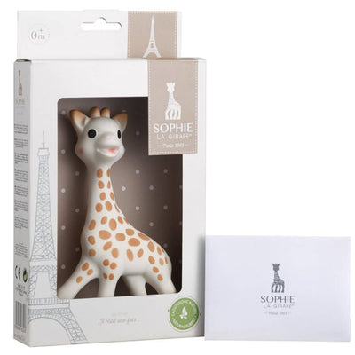 The Sophie La Girafe White Box-Classic by Calisson Toys features a cute, naturally rubber teether resembling a giraffe with brown spots, nestled in a clear box decorated with Eiffel Tower graphics and branding. A separate white card displays the iconic giraffe logo.