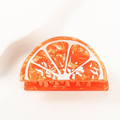 The Orange Slice Hair Claw Clip by Judson & Company measures 2.5 long and features a glossy marbled finish in a semi-circle shape that artfully resembles a sliced orange, offering both style and functionality.