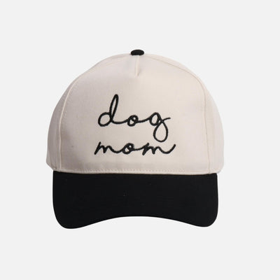 The Judson & Company dog mom baseball cap features a white crown, black brim, "dog mom" embroidered in black cursive on the front, and a snap back closure for adjustable fit.
