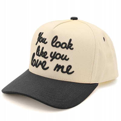 The "you look like you love me" Two Tone Baseball Cap by Judson & Company features beige and black panels, black cursive embroidery on the front, is made from 100% cotton, and has a snapback closure for adjustable comfort.