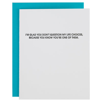 The Question Life Choices card by Chez Gagné is a funny anniversary letterpress card featuring black text on a white backdrop with the message, IM GLAD YOU DONT QUESTION MY LIFE CHOICES, BECAUSE YOU KNOW YOURE ONE OF THEM, on 100% cotton paper with a teal background.