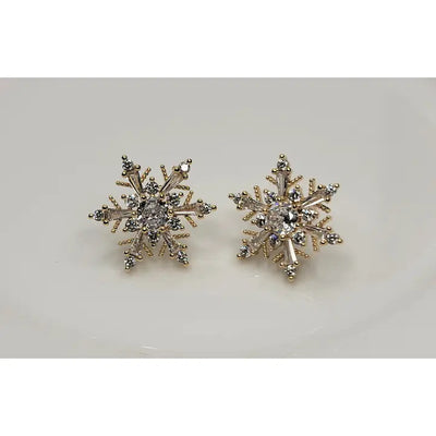 The BETTYOH INC CZ Snowflake Earrings feature a gold and silver snowflake design with sparkling stones and cubic zirconia accents, titanium posts, elegantly displayed on a white surface.