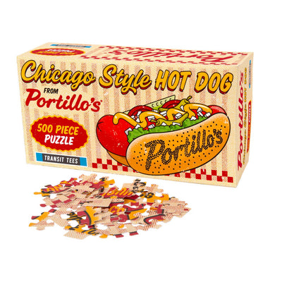 The Portillo's Hot Dog 500 Piece Puzzle by Transit Tees features a colorful Chicago-style hot dog with "Portillo’s" on the bun and loose pieces in front—an ideal gift for any Portillo’s puzzle enthusiast.