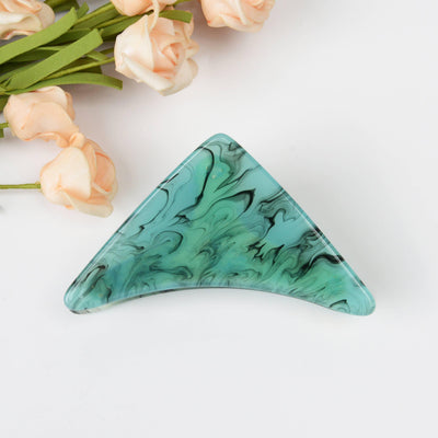 The SoapElenGlen Dark green triangle hair claw clip, crafted from acetate with a marbled dark green and black pattern, measures 3.46 x 2.12 inches and is shown on a white surface beside peach-colored artificial roses.